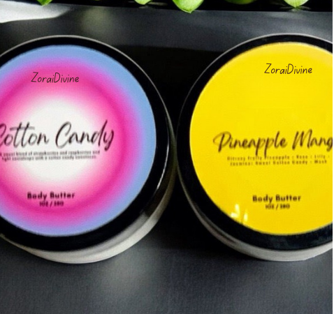Two containers of ZoraiDivine body butter, one pink and one yellow, on a dark surface.