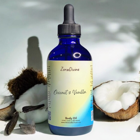 Bottle of ZoraiDivine Coconut & Vanilla body oil with coconuts and vanilla beans on a light background