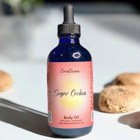 Bottle of ZoraiDivine Sugar Cookie body oil with cookies in the background