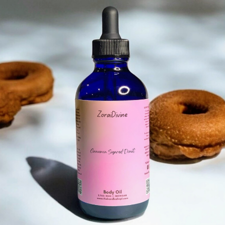 Bottle of Cinnamon sugared donut baby oil with two donuts on a light background