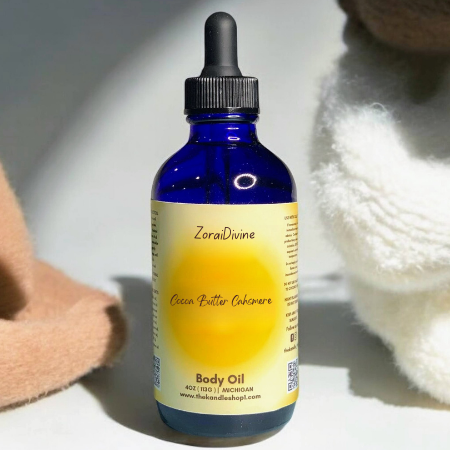 Blue bottle of Cocoa butter cashmere body oil with a dropper on a light background