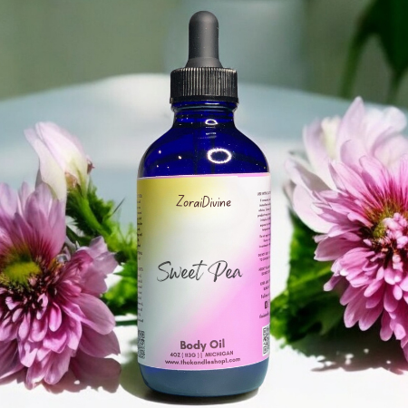 Bottle of ZoraiDivine Sweet Pea body oil with flowers in the background