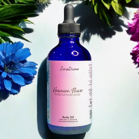 Bottle of ZoraiDivine Hawaiian Flower Body Oil with flowers in the background