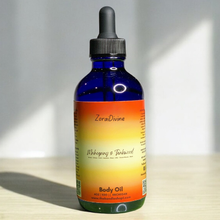 Blue bottle of Mahogany & Teakwood body oil with a dropper on a light surface.