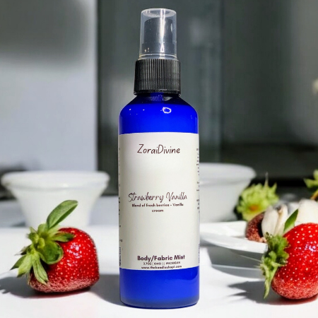 Body mist strawberry vanilla on a white conter with strawberries around the bottle.