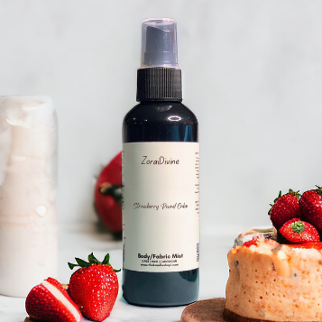 Bottle of ZoraiDivine Strawberry pound cake body mist with strawberries and cake on a white background