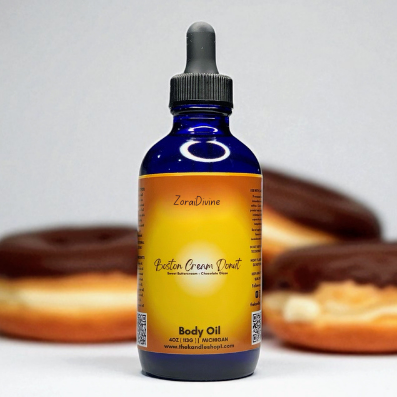 Bottle of ZoraiDivine Boston cream donut body oil with donuts in the background