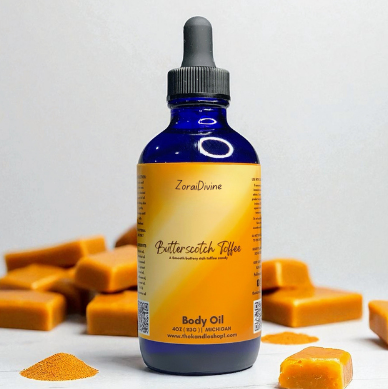 Bottle of ZoraiDivine Butterscotch Toffee body oil with butterscotch candy pieces on a white background