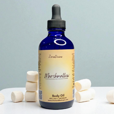 Bottle of ZoraiDivine Marshmallow Body Oil with marshmallows on a light gray background
