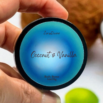 Hand holding a blue container labeled 'Coconut & Vanilla' body butter with blurred background