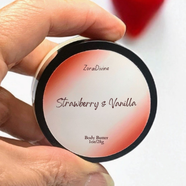 Hand holding a round container labeled 'Strawberry & Vanilla' body butter with a blurred heart in the background.