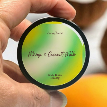 Hand holding a round container labeled 'Mango & Coconut Milk' body butter with coconuts in the background.