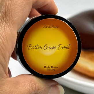 Hand holding a container labeled 'Boston Cream Donut' body butter with donuts in the background