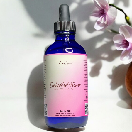Bottle of Enchanted Flower body oil with oranges and flowers on a white background
