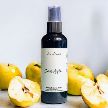 Body mist 'Sweet Apple' spray on a marble surface with apples around