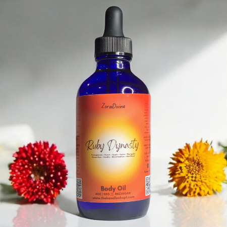 Bottle of Ruby Dynasty body oil with flowers in the background
