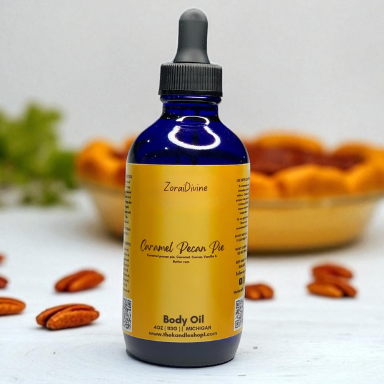 Bottle of caramel pecan pie body oil with pecans on a white surface