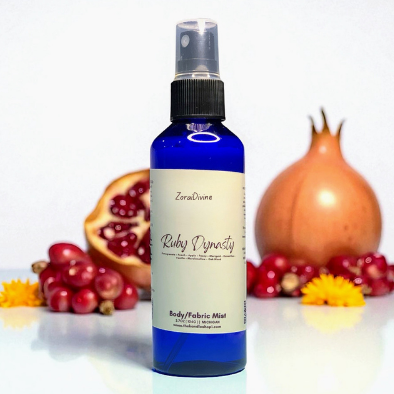 Body mist Ruby Dynasty on a white countertop with slices of pomegranate.