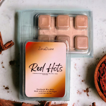 Wax melt 'Red Hots' packaging, surrounded by cinnamon sticks on a light background.