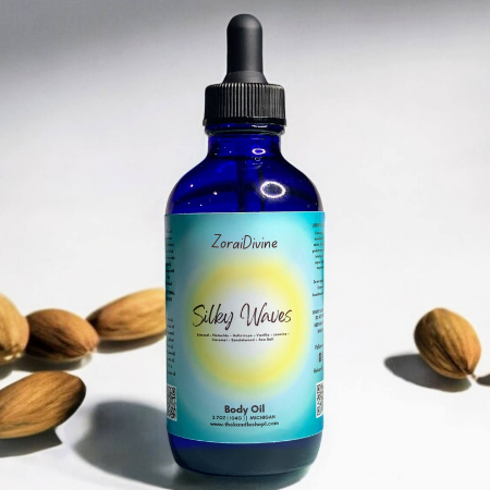 Blue bottle of ZoraiDivine Silky Waves Body Oil with almonds on a light background